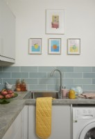 Kitchen with blue metro tiles showing the sink, artwork and crockery.
