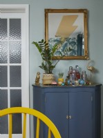 Dining room detail showing upcycled painted cabinet with drinks, gold ornaments and a mirror.