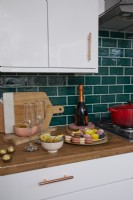 Detail of contemporary kitchen with green metro tiles and some Christmas food and drinks.
