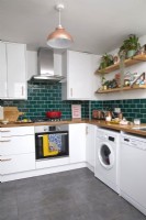 Contemporary kitchen with green metro tiles, open shelving and colourful accessories.
