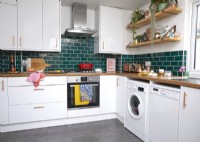 Contemporary kitchen with green metro tiles, open shelving and colourful accessories.