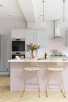 Modern pale pink and white kitchen with island and breakfast bar