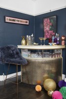 Living room with a gold drinks bar, dark blue painted walls and Christmas decorations.
