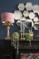 Living room detail showing the mantlepiece with gold ornaments, a lamp and candles.