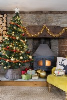 Country house living room with Christmas tree and wood burning stove in a stone and brick inglenook fireplace