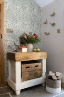 Butchers block style chunky table in a hallway against patterned botanical leaf wallpaper