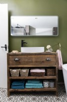 Bespoke handmade wooden vanity unit with white bathroom sink against a green wall