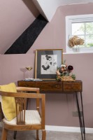 Detail of wooden desk and chair in pink attic bedroom