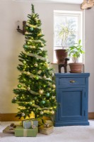 Christmas tree beside an upcycled shabby chic painted blue cabinet