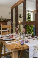Dining area with wooden dining table laid for Christmas in front of exposed wooden beams