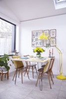 Open plan dining area with Ercol vintage chairs and a yellow floor lamp.