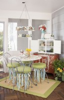 Dining area of 3-season porch with painted table, vintage postcard chandelier and cabinet storage