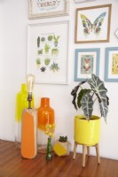 Mid Century sideboard detail showing retro vases, a lamp and botanical illustrations on the wall.