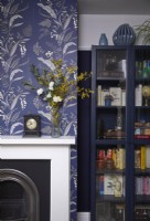 Dining room detail showing a fireplace with patterned wallpaper and a dark blue storage cabinet.