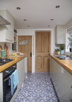 Galley kitchen in a Victorian house with wooden doors and a patterned flooring.