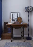 Bedroom corner detail showing Singer sewing machine table with vintage ornaments and a patterned floor lamp.