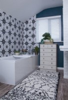 Bathroom with patterned tiles, blue painted walls and a vintage set of drawers.