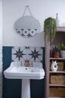 Bathroom detail showing sink, patterned tiles, vintage style mirror and open shelving storage.