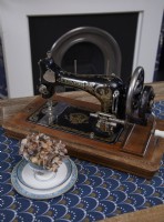 Detail showing a vintage sewing machine with a fireplace in the background.