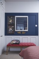 Bedroom detail showing navy blue and white wooden panelling and a coral pink stool.