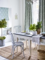 Dining room with green patterned curtains and roman blind