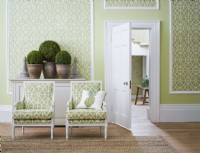 Green classic panelled room with chairs and view through to hall.