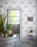 Table with house plants on in room with elephant wallpaper