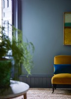 Blue painted wall with yellow chair and window shutters
