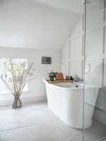 White roll top bath in classic white bathroom with panelled feature wall
