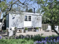 Guest room shepherds hut with outside loungers and dining area.