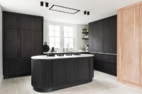 Contemporary dark kitchen with cooker on island.