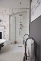 Bathroom with a walk in shower cubicle, herringbone tiling and flamingo wallpaper.