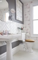 Bathroom showing sink, white herringbone tiling and flamingo wallpaper.