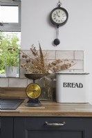 Kitchen detail showing grey cabinets, vintage scales and bread bin.