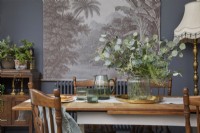 Dining area detail showing table with glassware, vintage wooden furniture, and botanical artwork.