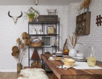 Dining area with a wooden table, industrial style shelving and white brick wallpaper.