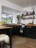 Modern kitchen with black cabinets and open shelving for crockery.
