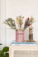 Bunches of dried flowers standing in a tin on top of a cabinet