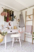 Corner of a craft room with an upcycled painted desk and chair and a designer cane ladder