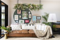 Brown leather sofa in front of a gallery wall with hanging faux plants
