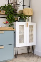 Pale pink cabinet with rattan doors in the corner of a kitchen