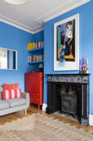 Wood burning stove and fireplace in a blue living room with red upcycled alcove cabinet and shelving