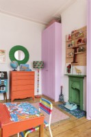 Built in pink wardrobe and painted green fireplace in a child's bedroom with hand painted school desk 