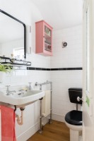 White and black tiled bathroom with pink wall mounted cabinet