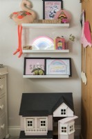 Display of toys and artwork on wall mounted shelves in childs room