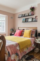 Colourful bedding on large wooden bed in modern bedroom 