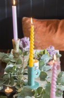 Detail of pastel coloured candles on dining table