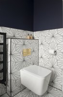 White toilet in modern bathroom with patterned floor and wall tiles
