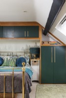 Built-in cabinetry in modern bedroom with brass bed