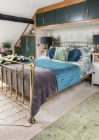 Brass bed in modern bedroom with built-in cabinets 